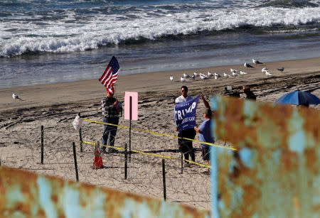 Supporters of U.S. President Donald Trump unfold a banner while standing in San Diego, U.S., and behind the border fence between Mexico and the United States, as seen from Tijuana, Mexico November 14, 2018. REUTERS/Jorge Duenes