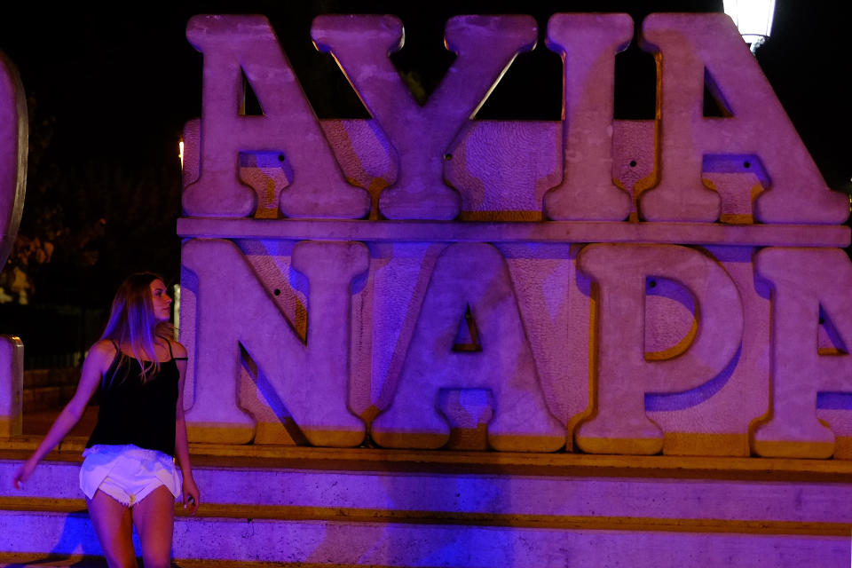 A tourist walks at a sculpture that read "I Love Ayia Napa" after pose for photos in the southeast resort of Ayia Napa in the easter Mediterranean island of Cyprus late Wednesday, July 17, 2019. A Cyprus police official says 12 Israelis have been detained after a 19-year-old British woman alleged that she was raped in the resort town of Ayia Napa. (AP Photo/Petros Karadjias)