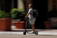 A man travels along a street atop an electric scooter in downtown San Diego , California