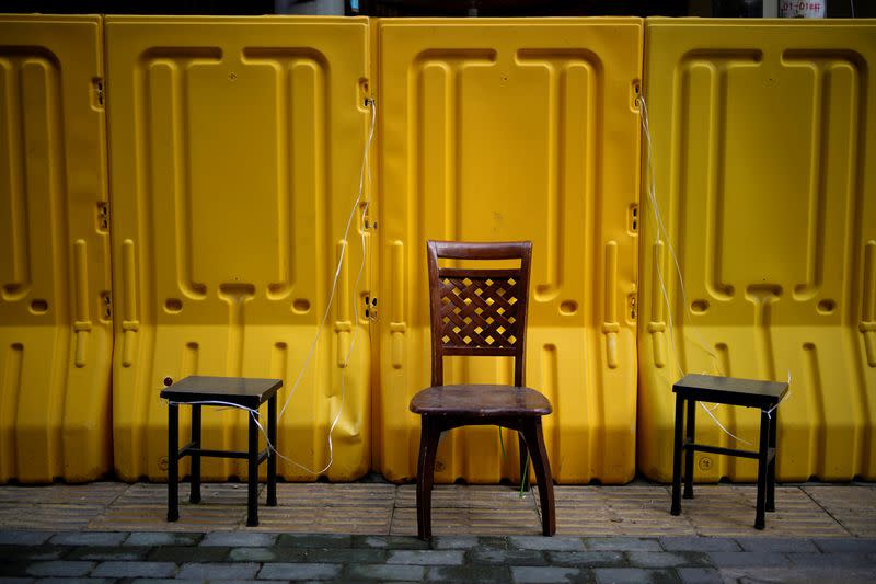 Chairs are set up to allow residents wanting to buy groceries to peer over barriers set up to ring fence a wet market on a street in Wuhan