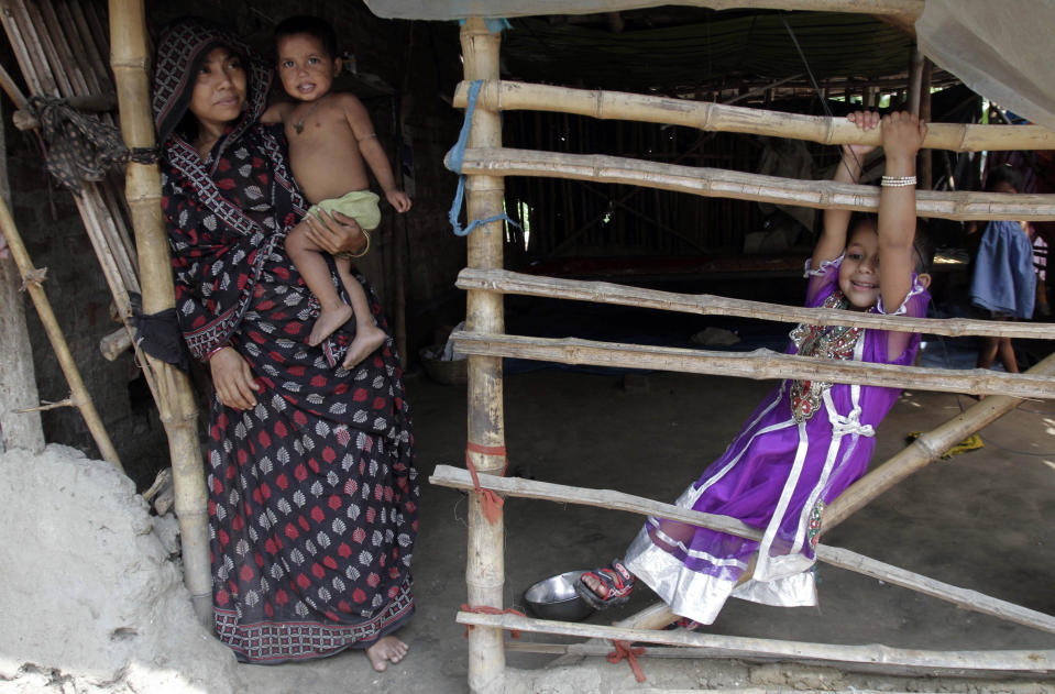 Rukhsar Khatoon, the last person in India to contract polio, hangs on to a bamboo fence, as her mother Sabeda Bibi stands beside her, at their home in Shahpara Village, 60 kilometers (40 miles) west of Kolkata, India, Thursday, March 27, 2014. In India, the scourge of polio ends with Khatoon, a lively 4-year-old girl who contracted the disease when she was a baby after her parents forgot to get her vaccinated. On Thursday, after three years with no new cases, the World Health Organization formally declared India polio-free. (AP Photo/Bikas Das)