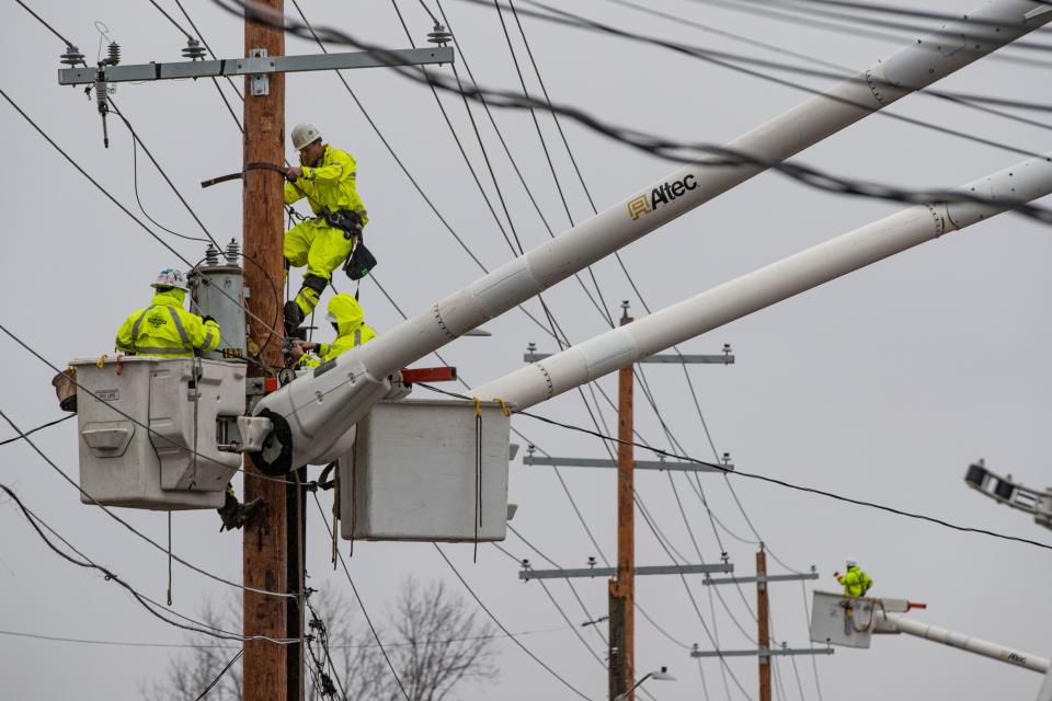 Electrical crews work to restore power along Oak Street as heavy rains fall Friday morning in Mayfield, Ky. Dec. 17, 2021