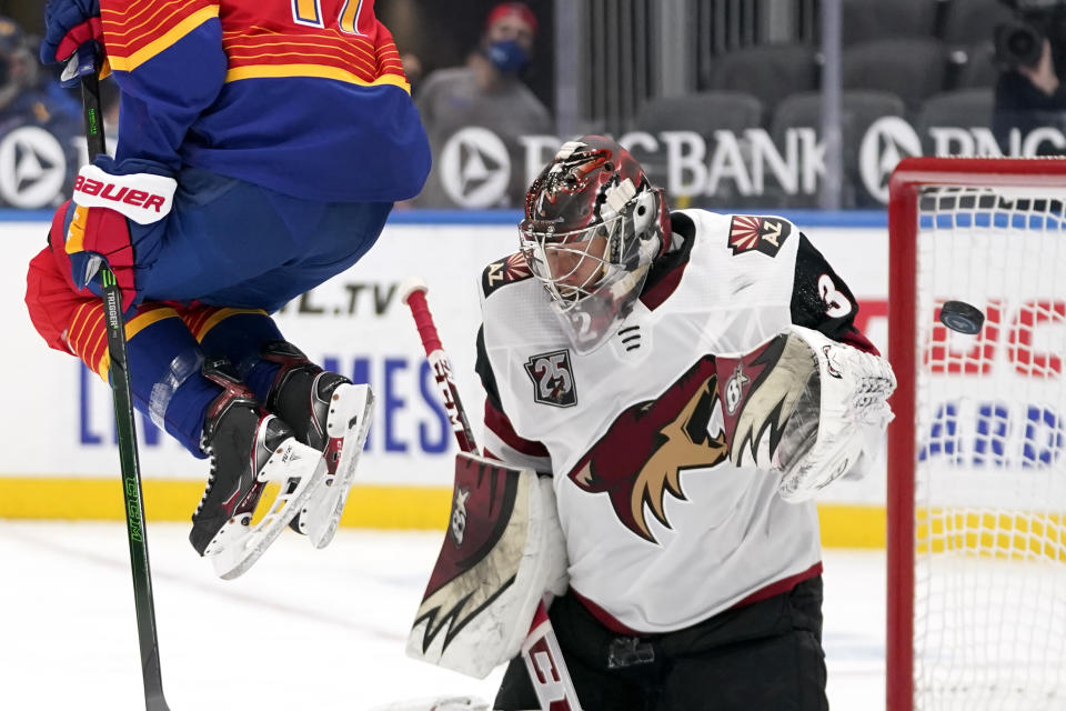 A puck is deflected by Arizona Coyotes goaltender Antti Raanta, right, as St. Louis Blues' Jaden Schwartz, left, leaps out of the way during the second period of an NHL hockey game Thursday, Feb. 4, 2021, in St. Louis. (AP Photo/Jeff Roberson)