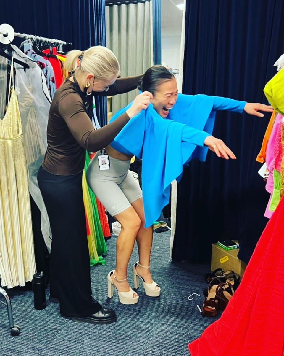 Poh Ling Yeow is shown trying to get a blue dress off with the help of a costume assistant