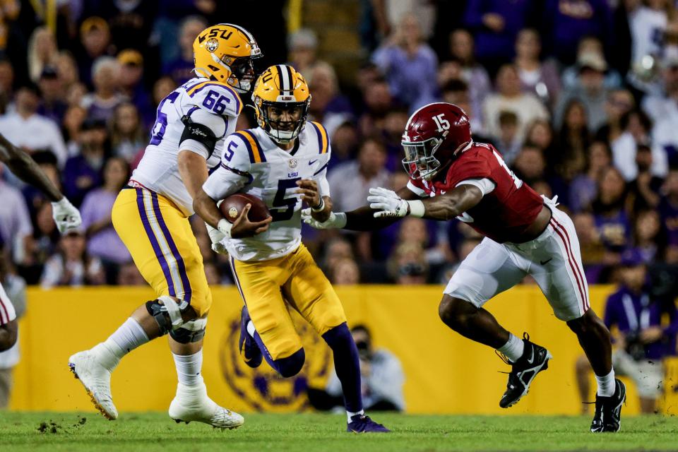 LSU quarterback Jayden Daniels (5) scrambles out the pocket against Alabama linebacker Dallas Turner (15) during the first half at Tiger Stadium.