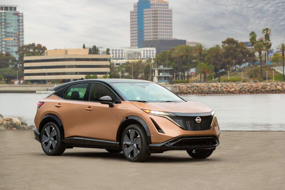 The Nissan Ariya parked next to water with a city skyline in the background.