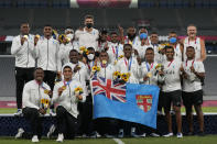 Fiji players and team staff poses with their gold medals and a national flag, after winning men's rugby sevens at the 2020 Summer Olympics, Wednesday, July 28, 2021 in Tokyo, Japan. (AP Photo/Shuji Kajiyama)