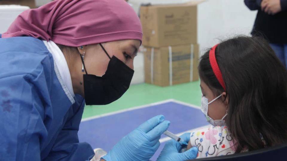 Una enfermera vacuna a una menor en Ecuador