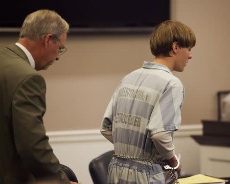 Dylann Roof (R), the 21-year-old man charged with murdering nine worshippers at a historic black church in Charleston last month, is helped to his chair by chief public defender Ashley Pennington during a hearing at the Judicial Center in Charleston, South Carolina July 16, 2015. REUTERS/Randall Hill