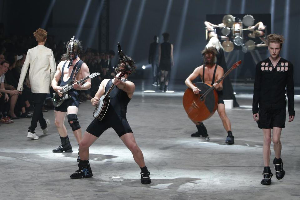 Models, right and left, wear creations by fashion designer Rick Owens as part of his men's fashion Spring-Summer 2014 collection, presented Thursday, June 27, 2013 in Paris, as Estonian metal/punk band Winny Puhh, centre, perform live. (AP Photo/Francois Mori)