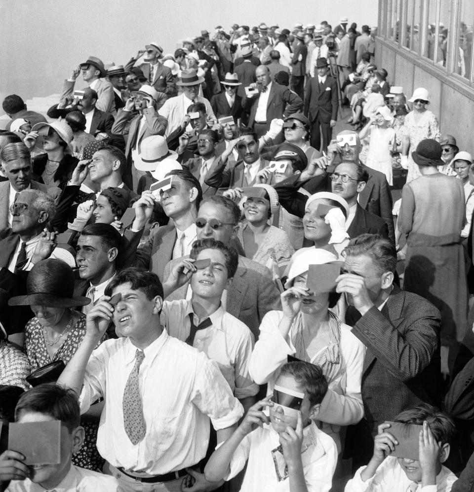 Eclipse watchers squint through protective film as they view a partial eclipse of the sun from the top deck of the Empire State Building on Aug. 31, 1932.<span class="copyright">AP</span>