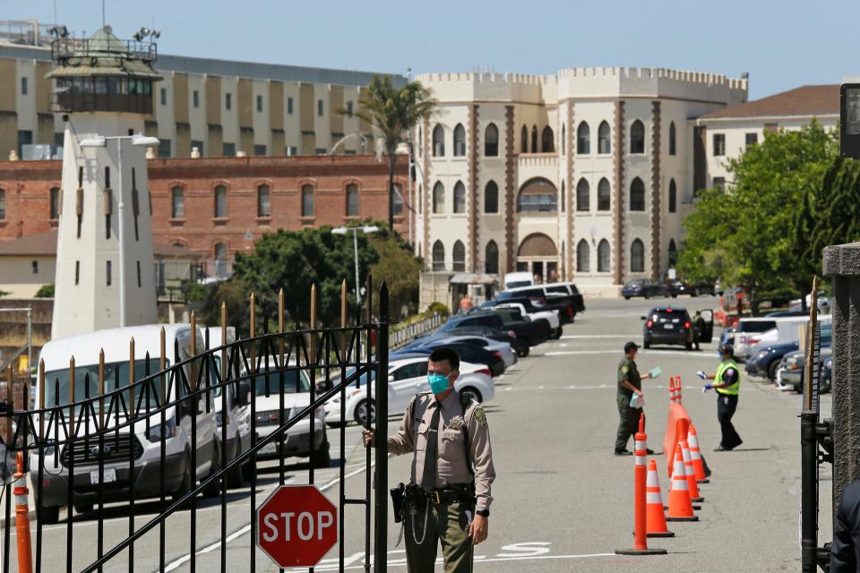 In this July 9, 2020, file photo, a correctional officer closes the main gate at San Quentin State Prison in San Quentin, Calif.