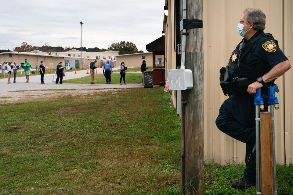 A sheriff's deputy oversees a line of voters at an early voting location in Lawrenceville, Georgia October 24, 2020.