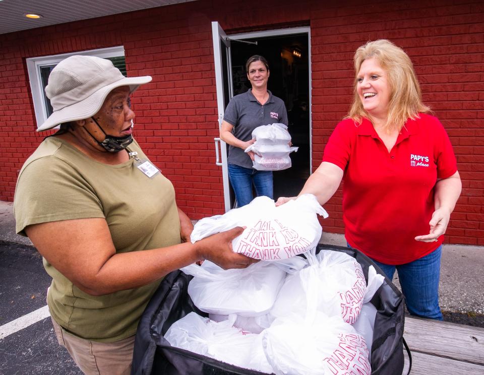 Minnie Taylor, left, with Marion Senior Services, gathers up the 46 prepared meals from Alicia Quest, center, and Wanda Homan, right, Wednesday morning at Papy's Place. The restaurant prepares 46 meals, four days a week, for Marion Senior Services. The seniors pick up the meals at the eatery.