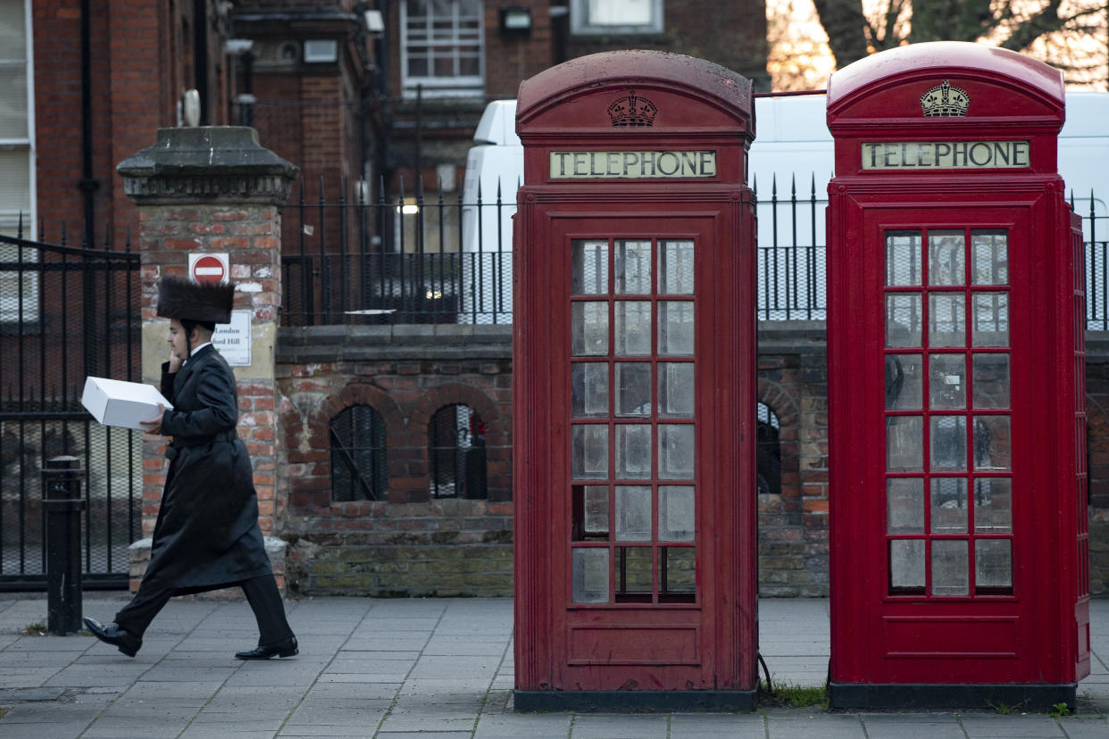 LONDON, ENGLAND - APRIL 08: A man walks past a pair of telephone boxes in Stamford Hill on the evening of the Jewish holiday of Passover on April 8, 2020 in London, England. The Jewish community is preparing to celebrate Passover amid COVID-19 home isolation and social distancing measures. (Photo by Hollie Adams/Getty Images)