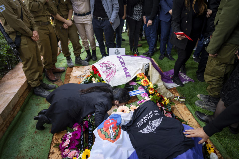 Family and friends of Israeli soldier Lt. Yaacov Elian mourn over his grave during his funeral at Kiryat Shaul cemetery in Tel Aviv, Israel, Friday, Dec. 22, 2023. Elian, 20, was killed during Israel's ground operation in the Gaza Strip, where it has been battling Palestinian militants in the war ignited by Hamas' Oct. 7 attack into Israel. (AP Photo/Oded Balilty)