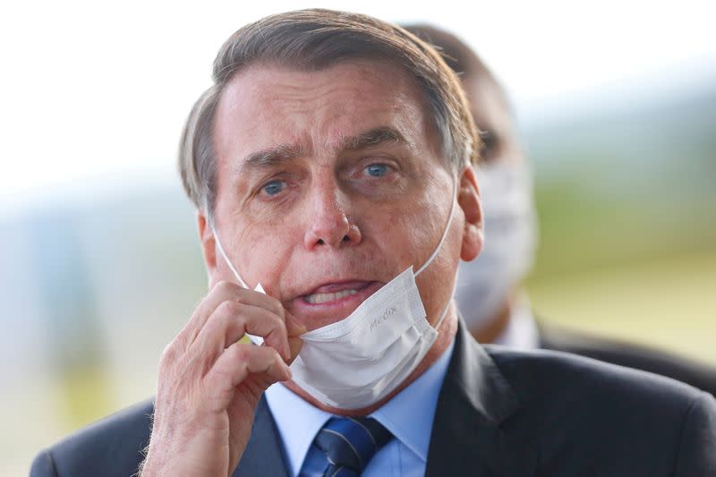 FILE PHOTO: FILE PHOTO: Brazil's President Jair Bolsonaro adjusts his mask as he leaves Alvorada Palace, amid the coronavirus disease (COVID-19) outbreak in Brasilia