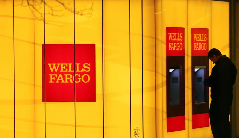 FILE PHOTO: A man uses an automated teller machine (ATM) at a Wells Fargo Bank branch on a rainy morning in Washington