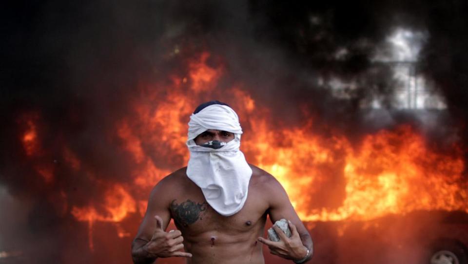 Un manifestante con el rostro cubierto y el torso herido se enfrentaba a las fuerzas leales a Nicolás Maduro en el primer día de la rebelión convocada por los líderes opositores Leopoldo López y Juan Guaidó en el este de Caracas, Venezuela, el 30 de abril de 2019 (RFI).