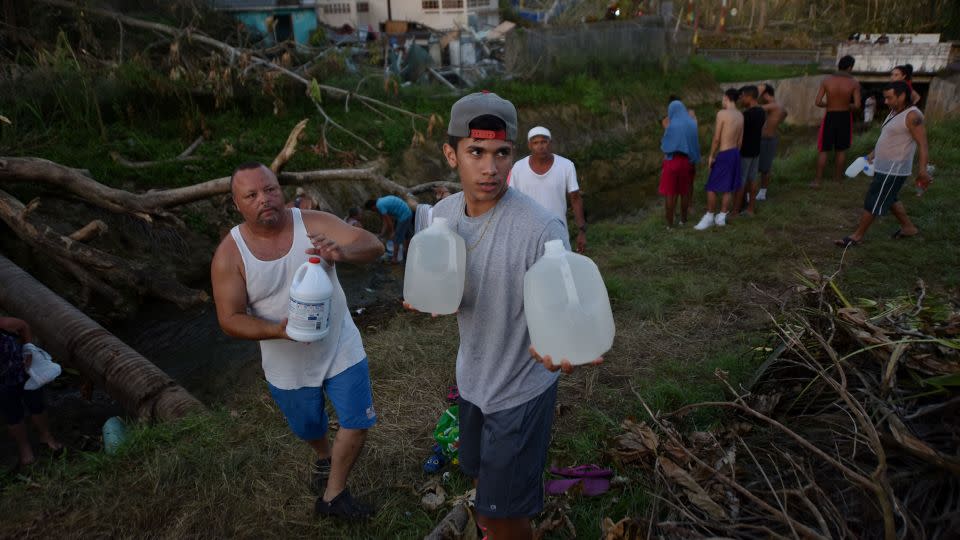 People carry water in bottles retrieved from a canal due to lack of water following passage of Hurricane Maria in Puerto Rico in September 2017. - Hector Retamal/AFP/Getty Images