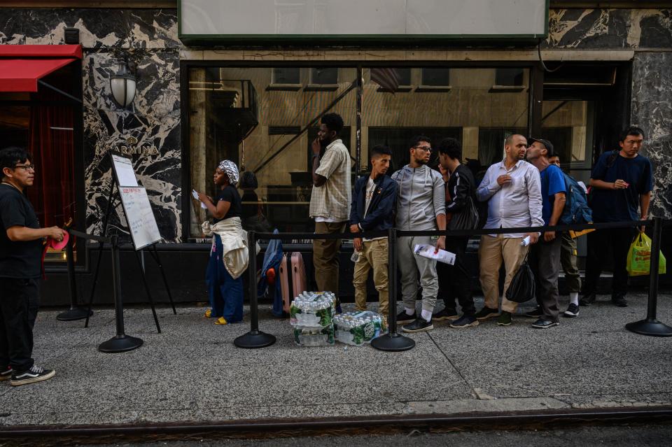 Migrants wait in line.