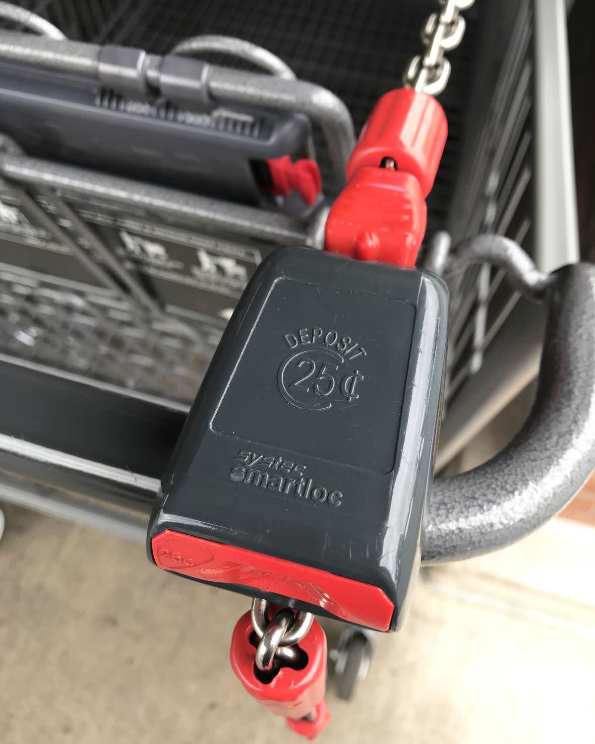 Closeup of quarter deposit on an Aldi cart outside an Aldi store, 'Deposit 25¢', cart handles and child's seat is blurred