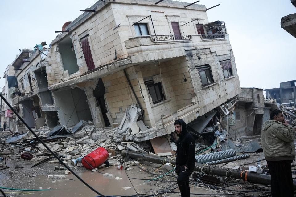 Residents stand in front of a collapsed building following an earthquake in the town of Jandaris, in the countryside of Syria's northwestern city of Afrin in the rebel-held part of Aleppo province, on February 6, 2023. - Hundreds have been reportedly killed in north Syria after a 7.8-magnitude earthquake that originated in Turkey and was felt across neighbouring countries.