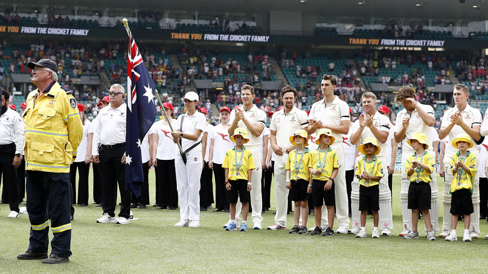 John Corry, pictured here looking on as players and crowd stand and applaud the efforts of firefighters.