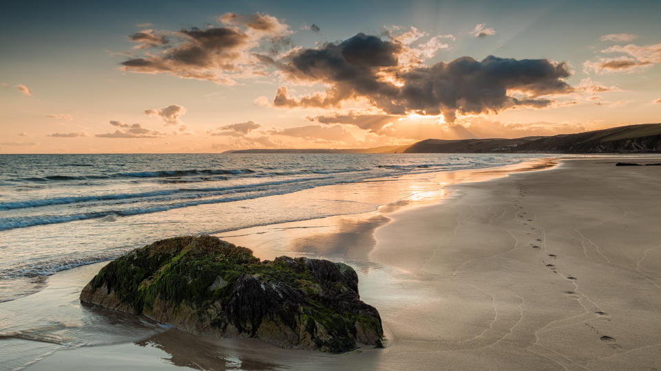 Tregantle Beach, Whitsand Bay, Cornwall. August 19, 2014. Footprints in the sand leading off to the sea,  Fluffy clouds during a beautiful sunset at Whitsand Bay.