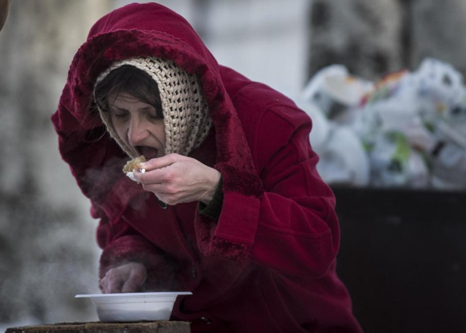 A local resident eats free food at a humanitarian aid center in Avdiivka, eastern Ukraine, Wednesday, Feb. 1, 2017. Freezing residents of an eastern Ukraine town battered by an upsurge in fighting between government troops and Russia-backed rebels flocked to a humanitarian aid center Wednesday to receive food and warm up. (AP Photo/Evgeniy Maloletka)