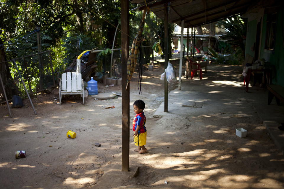 In this Sept. 15, 2012 photo, one-year-old Pedro Domiciano Dutra stands outside his home in the Quilombo Sacopa in Rio de Janeiro, Brazil. Quilombos are communities founded by escaped slaves or their descendents, and in Sacopa, the community is trying to save the grouping of brick houses and shacks nestled in the lush foilage of Brazil’s coastal rainforest where families have made their home for more than century but never legally owned. (AP Photo/Victor R. Caivano)