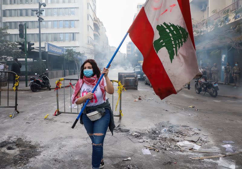 FILE PHOTO: A demonstrator carries a national flag during a protest in Beirut