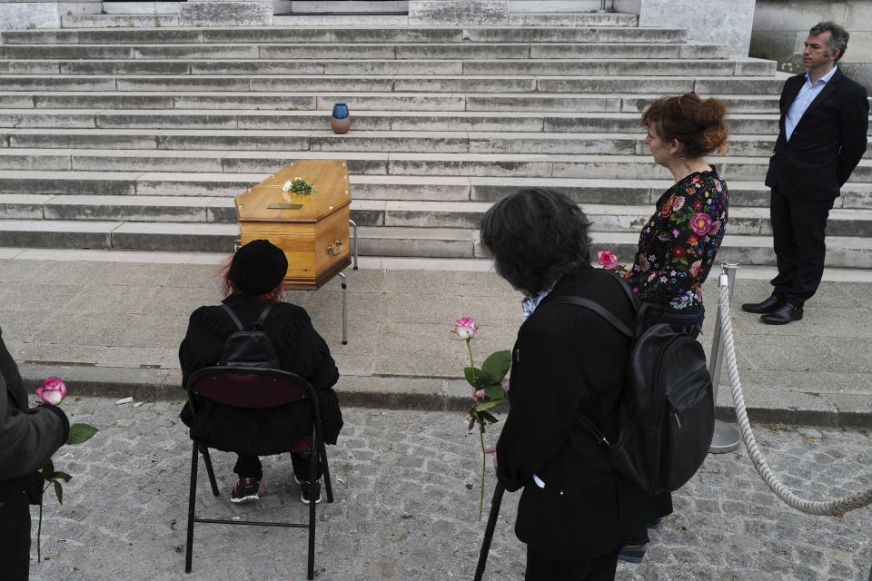 Mourners gather around the coffin of an 83-year-old man, during a funeral ceremony under the care of Paris undertaker Franck Vasseur, right, at Pere Lachaise cemetery in Paris, Friday, April 24, 2020. Vasseur says that dealing with a flood of coronavirus victims' bodies since March has turned his life into an infernal, head-spinning procession of death and that he feels robbed of his purpose by being unable to comfort families who cannot accompany bodies for cremation or gather in large numbers for funerals. (AP Photo/Francois Mori)