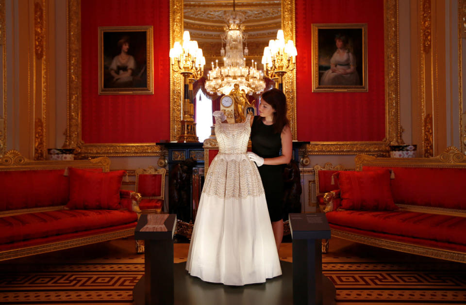 A member of staff of the Royal Collection poses with a dress worn by Britain’s Queen Elizabeth