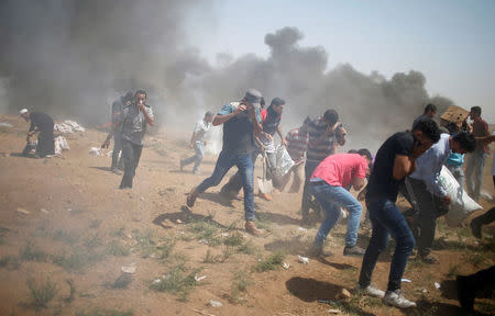 Palestinian demonstrators run for cover from tear gas fired by Israeli troops during a protest marking al-Quds Day, (Jerusalem Day), at the Israel-Gaza border, east of Gaza City June 8, 2018. REUTERS/Mohammed Salem