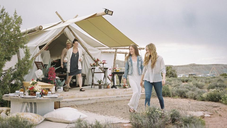 group of friends enjoying an outdoor meal a tent in the background