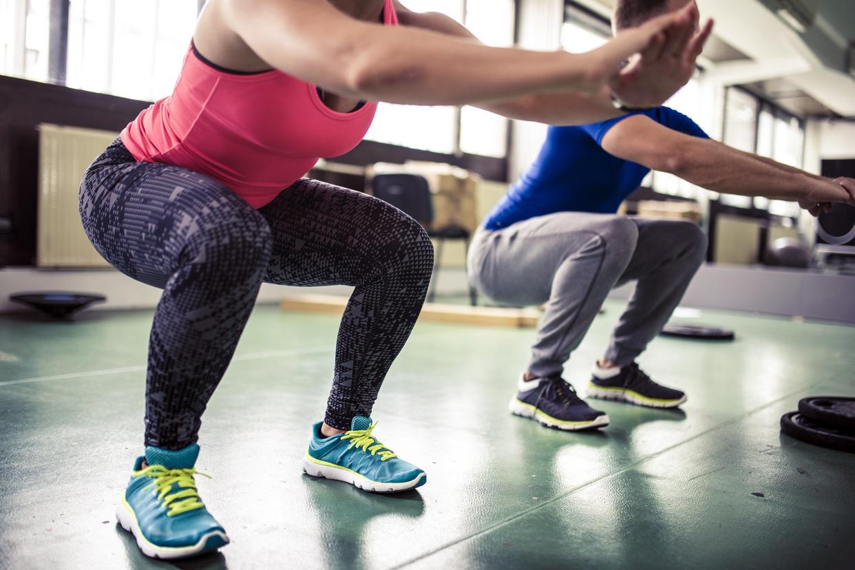 two people in gym doing squats