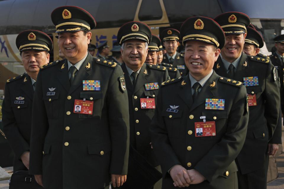 Delegates from China's People's Liberation Army (PLA) share a light moment as they arrive to attend a plenary session of the National People's Congress at the Great Hall of the People in Beijing, Saturday, March 4, 2017. China will raise its defense budget by about 7 percent this year, a government spokeswoman said Saturday, continuing a trend of lowered growth amid a slowing economy. (AP Photo/Andy Wong)