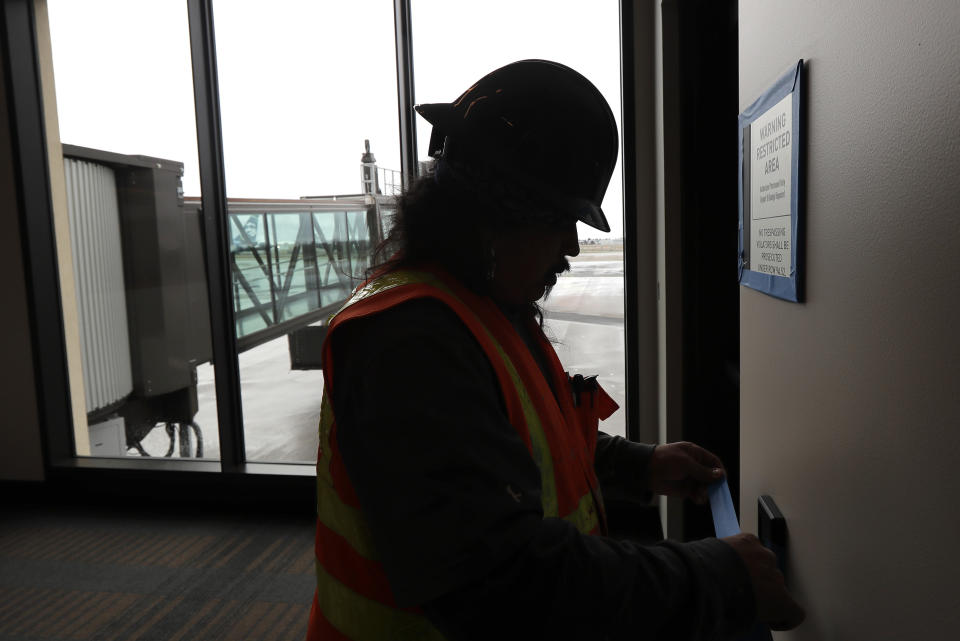 FILE- In this Jan. 23, 2019, file photo Dave McLeod tapes off trim as he prepares to paint a wall near a gate in the new passenger terminal at Paine Field in Everett, Wash. Alaska Airlines says it will delay the start of commercial passenger service at the new terminal by at least three weeks due to the ongoing partial shutdown of the federal government, as the officials who must sign off on a final environmental assessment are on furlough. (AP Photo/Ted S. Warren, File)