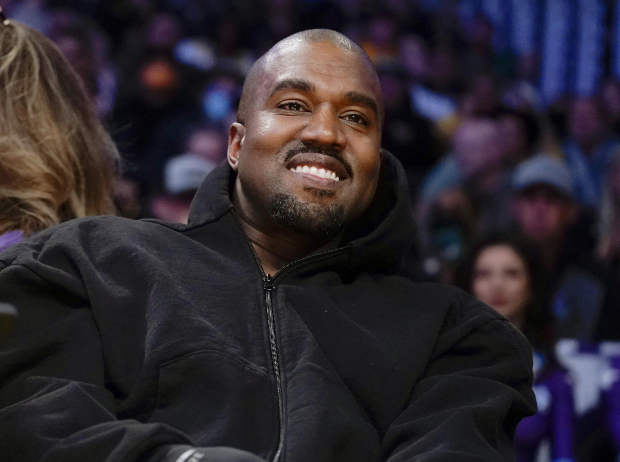 FILE - Kanye West, known as Ye, watches the first half of an NBA basketball game between the Washington Wizards and the Los Angeles Lakers in Los Angeles, on March 11, 2022. Adidas’ breakup with rapper Kanye West and the inability to sell his popular Yeezy line of shoes helped batter the company’s earnings at the end of last year. The German shoe and sportswear maker said Wednesday, March 8, 2023, that higher supply costs and slumping revenue in China also helped lead to a net loss of 513 million euros or $540 million in the fourth quarter.(AP Photo/Ashley Landis, File)
