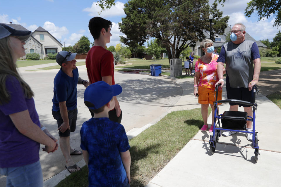 Terri Donelson and her husband, Stephen, right, are greeted by friends, family and neighbors after his arrival at his home in Midlothian, Texas on Friday, June 19, 2020. A trick doctors around the world shared with each other: Flip COVID-19 patients over from their backs to their stomach. It’s called proning and it takes pressure off the lungs, which lie closer to the back. Donelson stayed on his belly about 16 hours a day early on, as his doctors watched his oxygen levels improve. (AP Photo/Tony Gutierrez)