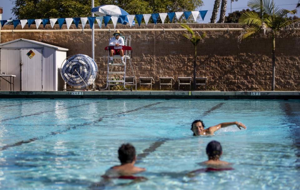 Swimmers in a public pool near a lifeguard.