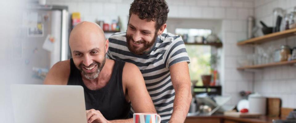 Gay couple using laptop in the kitchen