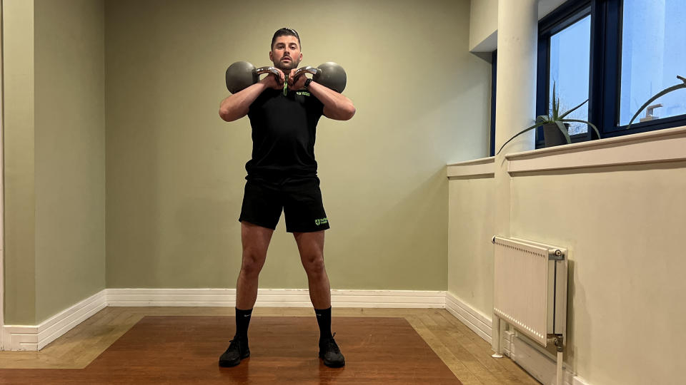 Sam Quinn, a strength coach from Nuffield Health, demonstrates a kettlebell shoulder press