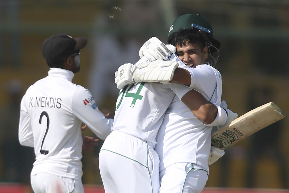 Pakistan's Abid Ali, right, celebrates his century with teammate Shan Masood against Sri Lanka during the third day of their second Test cricket match at National Stadium in Karachi, Pakistan, Saturday, Dec. 21, 2019. (AP Photo/Fareed Khan)