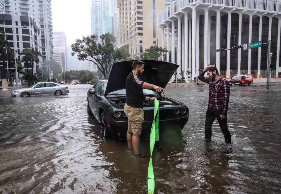 Bastan Vívala, left, discusses where to tie a tow rope on a stranded car with his friend, the car’s driver. Tropical Storm Eta slammed into Miami leaving motorists crossing the intersection of SW 13th Street and Brickell Avenue stuck in flood water due to its deluge on Monday, November 9, 2020.