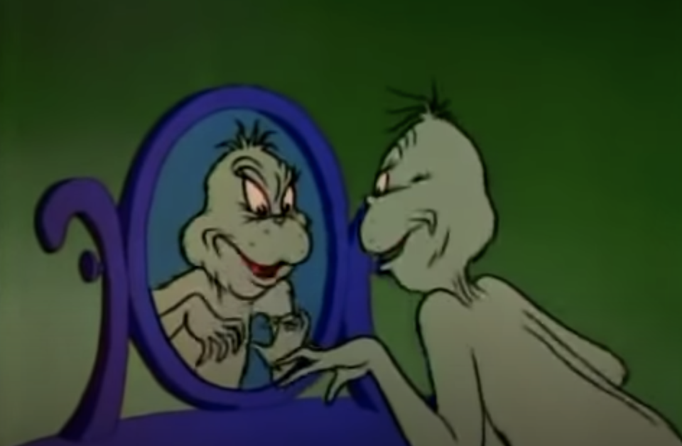 The grinch looking menacingly into the mirror