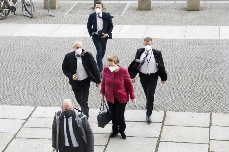 German Chancellor Angela Merkel, center, arrives for a parliament session about a new law to battle the coronavirus pandemic at the Bundestag at the Reichstags building in Berlin, Germany, Friday, April 16, 2021. (AP Photo/Markus Schreiber)