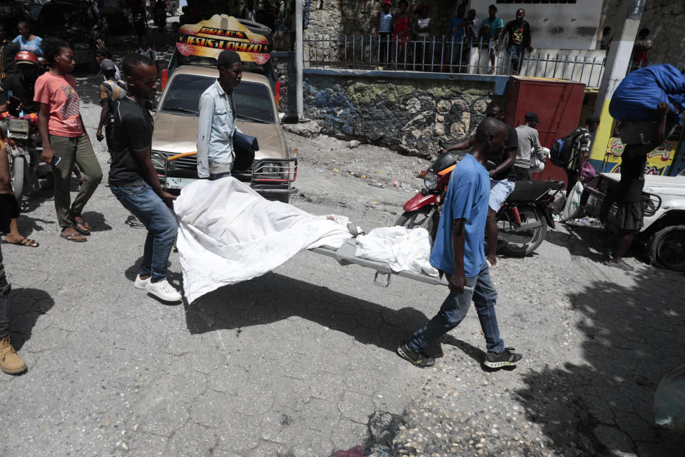 Morgue workers carry a body to an ambulance during gang violence in the Carrefour-Feuilles district of Port-au-Prince, Haiti, Tuesday, Aug. 15, 2023. (AP Photo/Odelyn Joseph)