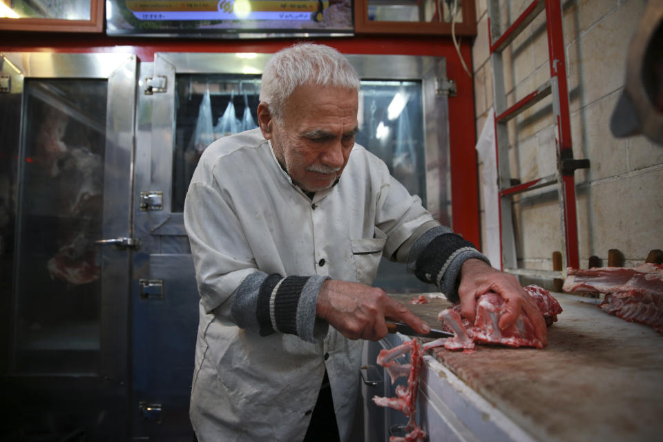 In this Thursday, Feb. 7, 2019 photo, butcher Ghasem Olfatian works at his shop in Tehran, Iran. The economy faces multiple struggles as the country marks the 40th anniversary of the Islamic Revolution. Inflation continues to rise as its currency depreciates and university graduates are unable to find jobs. Some of the challenges stem from the re-imposition of U.S. sanctions while other problems date back to the time of the revolution. (AP Photo/Vahid Salemi)